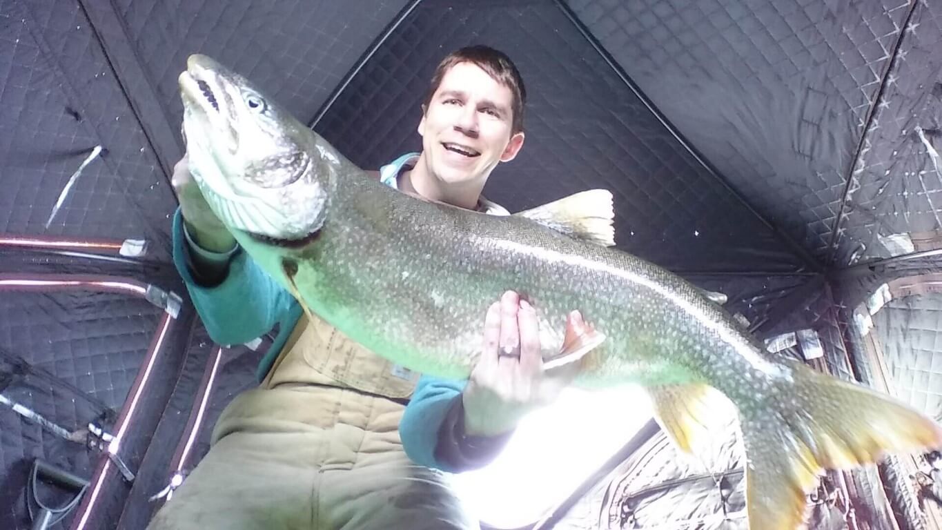 Angler holding a lake trout caught while ice fishing on frozen-over Lake Superior outside of Duluth, Minnesota